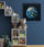Kids' room with white shelf, toys, books and plush bin, dark blue wall and hardwood floor, space-themed Planet Earth painting poster