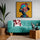 Künstlerisches Poster mit einer weiblichen Silhouette, geschmückt mit leuchtenden Blumen, auf hellgelbem Hintergrund. Über einem türkisfarbenen Sofa aufgehängt, fügt es sich perfekt in eine warme Dekoration mit Grünpflanzen, Naturholz und ethnischen Akzenten ein. Ideal für ein modernes und lebendiges Interieur.