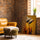 African women wall art on a brick wall with leather armchair, two women in straw hats and golden shawls, warm earthy tones
