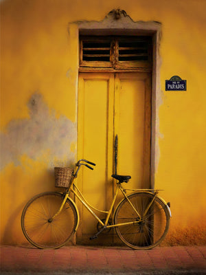 Bicyclette rétro jaune appuyée contre une façade ensoleillée, ambiance méditerranéenne.