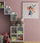 Framed fairy wall art hanging above a kids' bookshelf