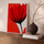 Red flower canvas wall art on coral background above a sideboard in a modern living room