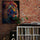 Pop art lion canvas in blue, red, orange, and yellow on a red brick wall; retro setup with white console, vinyl records, turntable, amp, speaker, and a green plant