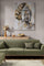 Large gold Buddha canvas hanging on the wall of a modern living room with a green sofa, light wood furniture, and natural decor