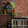 Bold, colorful street art monkey painting on a red brick wall above a white console with vinyl records, a turntable, and a plant; vintage, music-themed decor