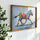 Framed rainbow zebra art print on a white wall with greenery