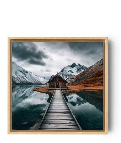 Foto van een afgelegen houten chalet, aan de oever van een vredig meer, omringd door besneeuwde bergen. De houten steiger leidt de blik naar de hut en creëert een knusse en meeslepende sfeer. Perfect voor een natuurlijke en rustgevende muurdecoratie.