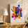 Vibrant geometric abstract wall art for living room decor, styled above an oak sideboard with a lamp