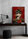 Dark wood desk with black lamp, stacked books, pencil cup, small plant, black ottoman, framed Matryoshka wall art