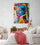 Modern master bedroom with double bed, white sheets, red throw, wicker chair, wooden dresser, woman portrait wall art