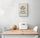 Un petit tableau de décoration beige avec une illustration de pain de campagne est suspendu au mur blanc. Sous le tableau cuisine une table et deux chaises blanches