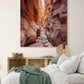  une toile  avec un paysage de canyon est situé dans une chambre à coucher. Le lit en dessous est recouvert d'une couverture verte et est entouré de plusieurs coussins. Un meuble en bois se trouve à côté du lit, sur laquelle reposent quelques livres.