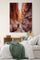 Canyon landscape canvas wall art displayed in a bedroom; bed with green blanket and multiple pillows, wooden nightstand with books