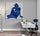 Modern home office with large white desk, rolling chair, navy cushion, floor lamp, light gray wall, and abstract blue woman canvas wall art
