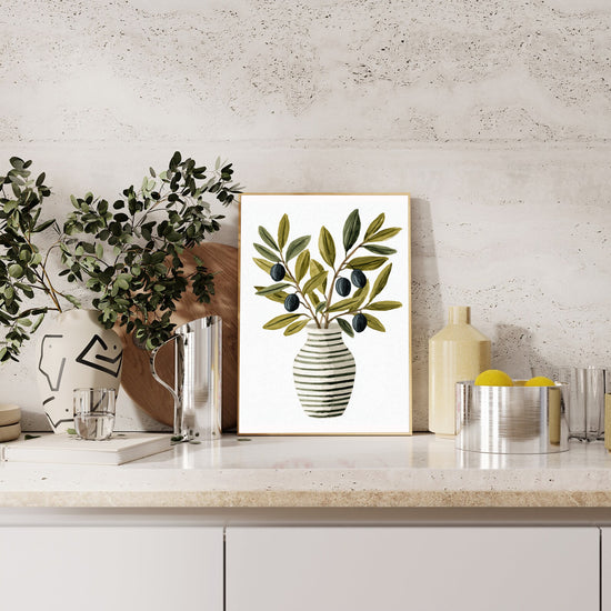 Close-up of art print with a black and white striped vase containing olive branches with green leaves and black olives, against a clean white background.