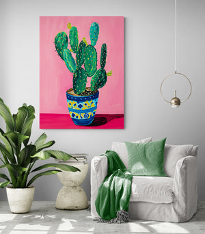 living room area, comfy chair, green cushion and throw, side table, large green plant, light gray wall, pendant lighting, pink cactus canvas