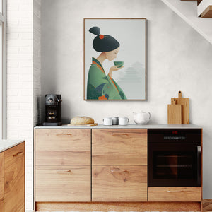 Cuisine moderne avec un tableau japonais représentant une geisha en kimono vert buvant une tasse de thé, accroché au mur au-dessus d’un meuble en bois avec machine à café, pain et vaisselle