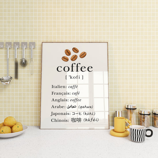 Tableau déco cuisine affichant le mot café traduit en plusieurs langues, posé sur un plan de travail avec mugs et bocaux.