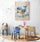 A painting of a smiling blue whale swimming through clouds, placed in a children's playroom with wooden furniture and educational toys on a woven rug.