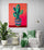 living space with comfortable armchair, green cushion and throw, side table, large green plant, light grey wall, hanging light, red cactus canvas.