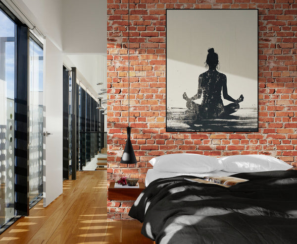 Modern bedroom with an exposed brick wall, bed with black and white sheets, and a painting of a female silhouette in a meditation pose. Natural light highlights the zen and urban ambiance of this apartment.