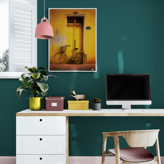 Vintage yellow bicycle artwork in a modern office with a green wall and light wood desk.
