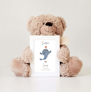 A teddy bear holding a personalized baby frame