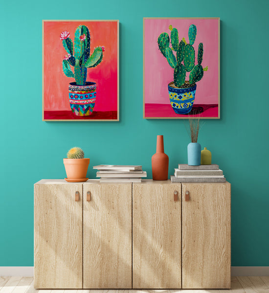 Deux tableaux colorés de cactus sont accrochés au-dessus d'un buffet moderne en bois clair, apportant une touche artistique vivante à un salon aux murs turquoise