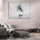 Zen wall decor of a lone fisherman in a boat before misty mountains, hung above a gray sectional in a modern living room with designer coffee table and gray rug