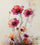 un papier peint artistique orné de fleurs roses éclatantes, peintes dans un style à la fois moderne et expressif. Les pétales sont rehaussés de nuances de fuchsia, de corail et d’orange, avec des éclaboussures de peinture qui ajoutent une touche abstraite et dynamique. Les tiges fines et élancées accentuent la verticalité du motif, tandis que le fond clair met en valeur chaque détail coloré.