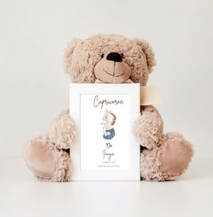 A cute teddy bear holds a frame with a custom Capricorn sign print, featuring a little unicorn with baby birth details.