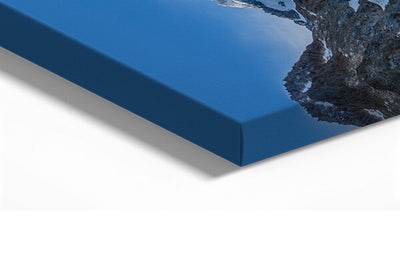 Gros plan sur l’angle d’un tableau imprimé sur toile, tendue sur un châssis en bois. L’image montre les détails de la texture toile et l’impression couleur bleue avec un paysage de montagne partiellement visible. Idéal pour illustrer la qualité d’un tirage sur toile haut de gamme.