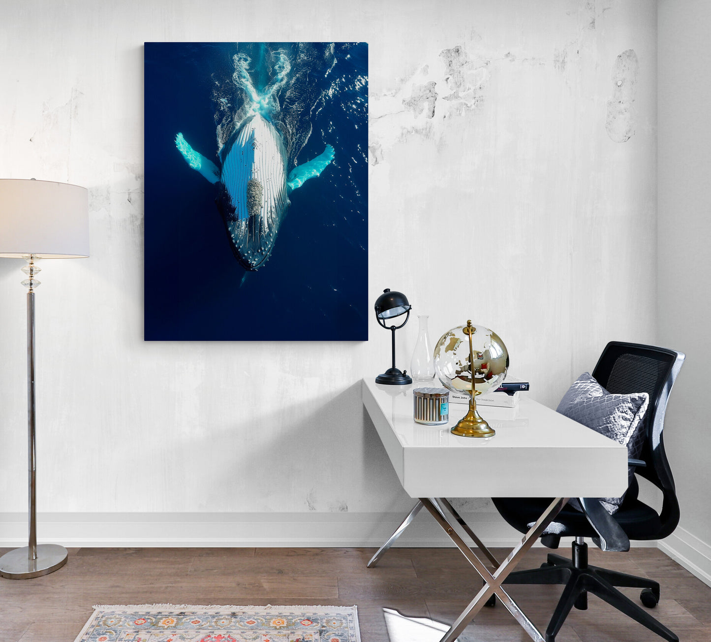 grand bureau blanc, pieds en metal, objets décoratifs, chaise sur roulettes, coussin bleu, lampe sur pied, mur blanc, affiche bleu baleine.