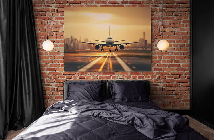 Dans une chambre au style industriel, un tableau grand format d'un avion au coucher du soleil complète le look brut des murs en brique.
