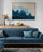 Un salon avec un canapé bleu, des coussins assortis, et un tableau horizontal représentant une plage avec des vagues bleues s'écrasant sur le sable beige accroché au mur.