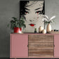 Commode rose avec dessus en bois affichant un tableau de geisha, entouré de plantes décoratives.