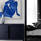 commode bleu nuit, vase décoratif, entré de chambre parentale, mur blanc, poster femme couleur bleu foncé.