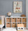 Baby nursery with rocket wall art above a dresser with wicker baskets, beside a globe, under a gray ceiling