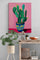 Styled wood dresser with decor accents, wicker basket, jars, small raised plant, textured wall with modern cactus poster