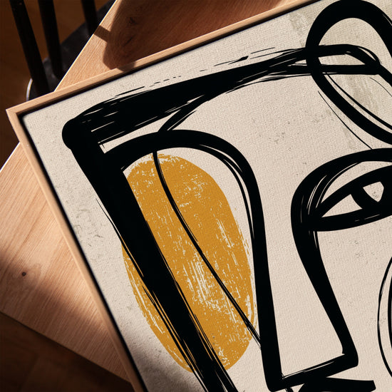 Tableau abstrait formes organiques noires et ocre sur fond beige posé sur table salon moderne