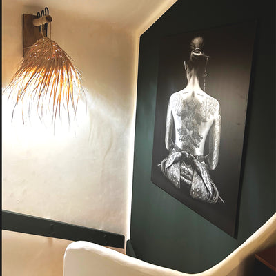 Photo partagée par un client montrant un tableau japonais en noir et blanc d’une femme tatouée de dos, habillée en geisha, imprimé sur aluminium et accroché dans une montée d’escalier au style zen et moderne.