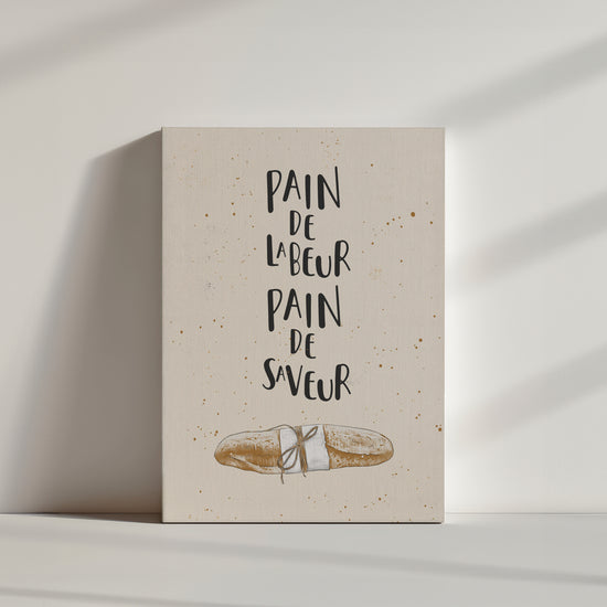 Sur un fond beige, une illustration d'une baguette trône aux centres de l'image. On peut également lire la citation "Pain de labeur, pain de saveur". Les couleurs sont douces et neutres