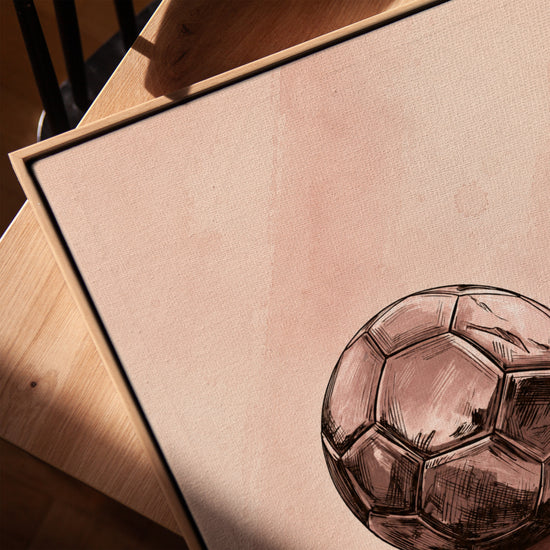 Tableau décoratif ballon de foot style esquisse tons roses sur table avec cadre chêne doré