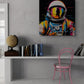 Dans une pièce avec des murs texturés en blanc, le tableau est à côté d'une étagère avec des livres, un globe terrestre, et une chaise rose. L'effet est à la fois minimaliste et vibrant.