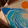 Abstract blauw canvas met golfmotief en oranje zon, in lijst van goudkleurig eiken op moderne salontafel