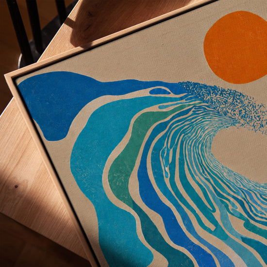 Abstract blauw canvas met golfmotief en oranje zon, in lijst van goudkleurig eiken op moderne salontafel