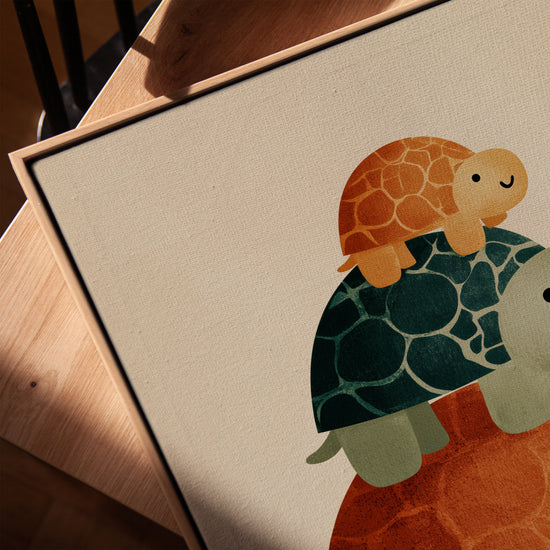 Tableau chambre bébé trois tortues empilées couleurs douces exposé avec cadre chêne doré