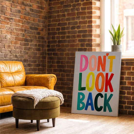 Don't Look Back colorful typography wall art on brick wall with camel leather armchair