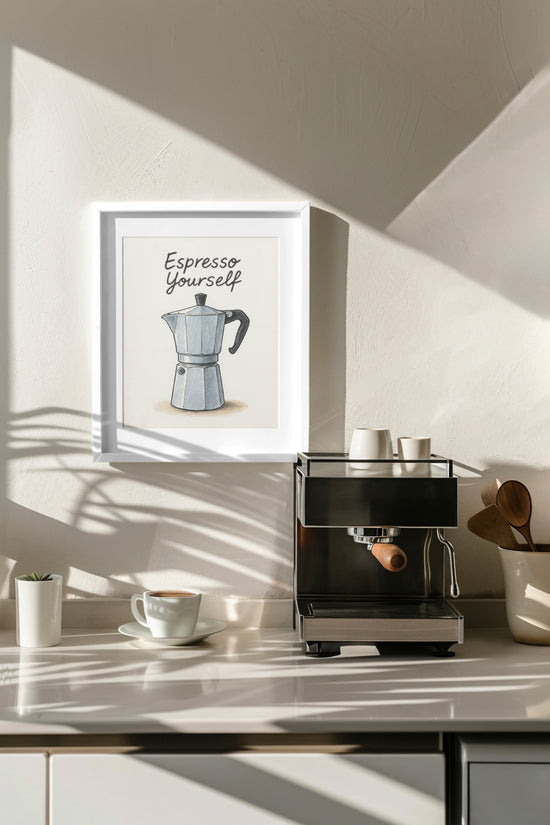 Modern kitchen wall decor featuring an illustrated Italian coffee maker poster with the phrase "Espresso Yourself," housed in a white frame above a coffee machine, surrounded by wooden cups and accessories.