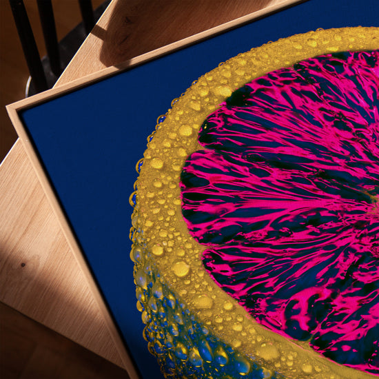 Leinwandbild Zitrone Pop Art in Fuchsia auf Blau mit Eichenrahmen in Goldton, auf Tisch platziert, moderne Deko